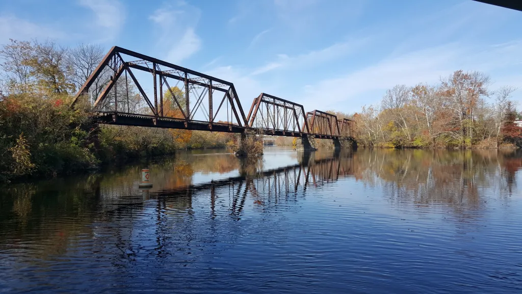 Steel truss bridge that spans the Lehigh River surrounded by trees under a clear blue sky.